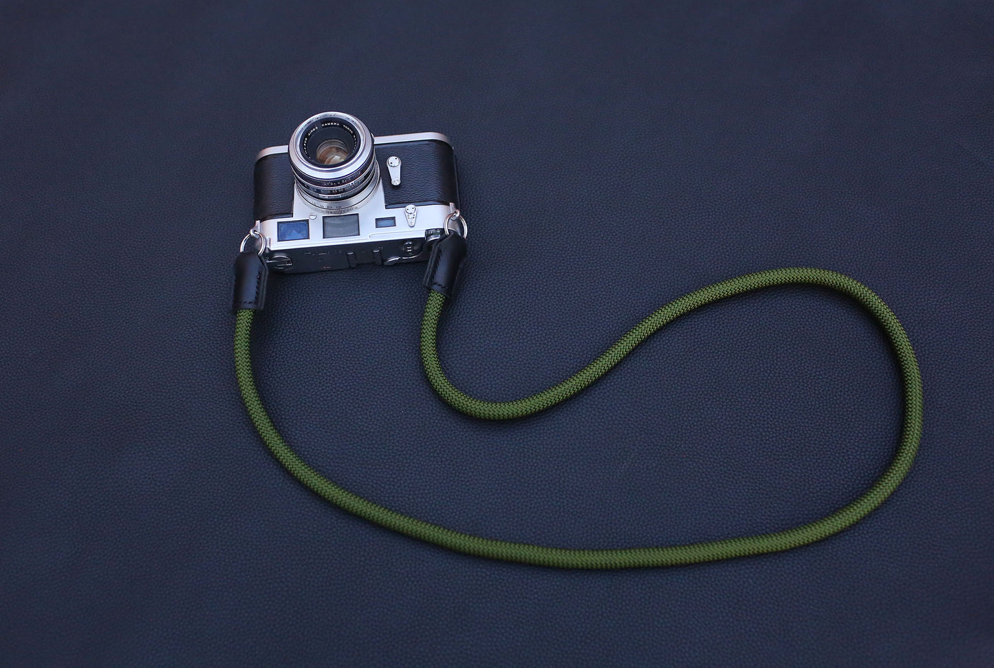 minimal profile rope camera strap on black background