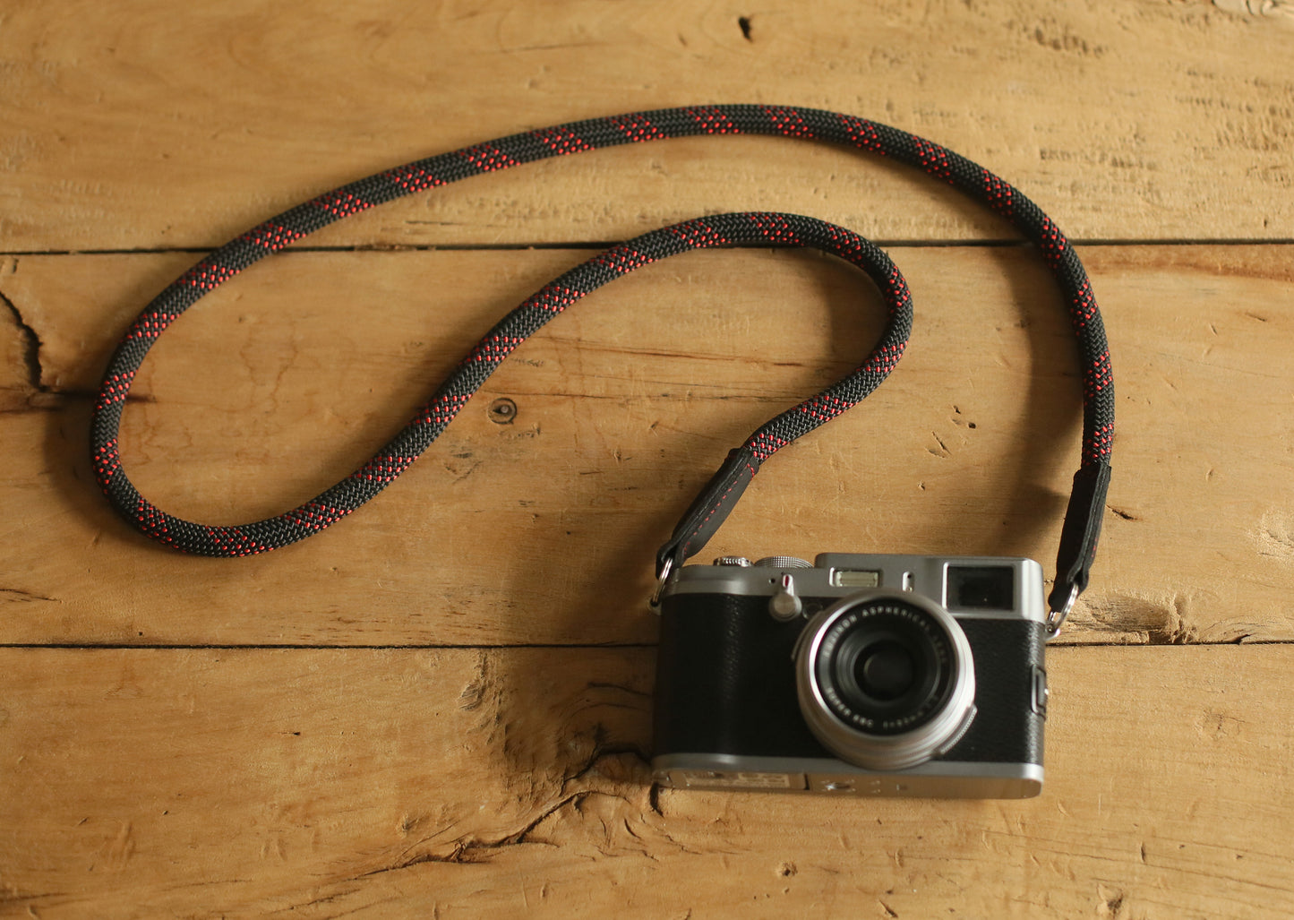 camera with black and red woven rope strap on wooden table