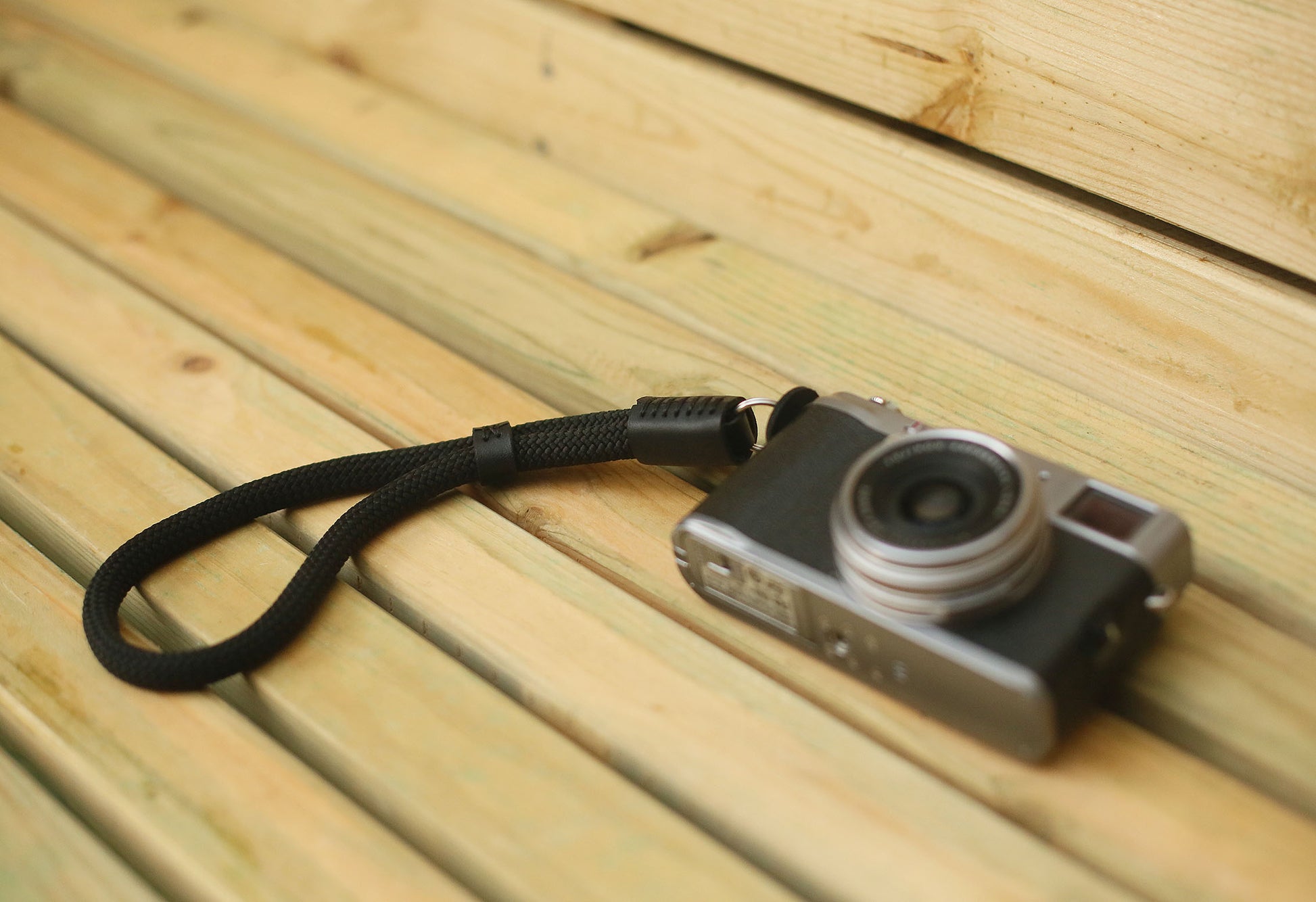 Flat lay of black rope wrist strap with vintage camera