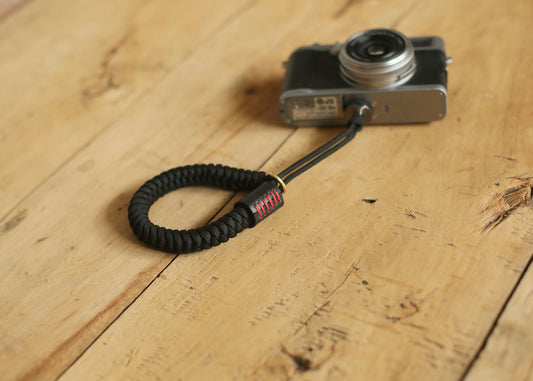 Black rope and leather wrist strap with red stitching close-up