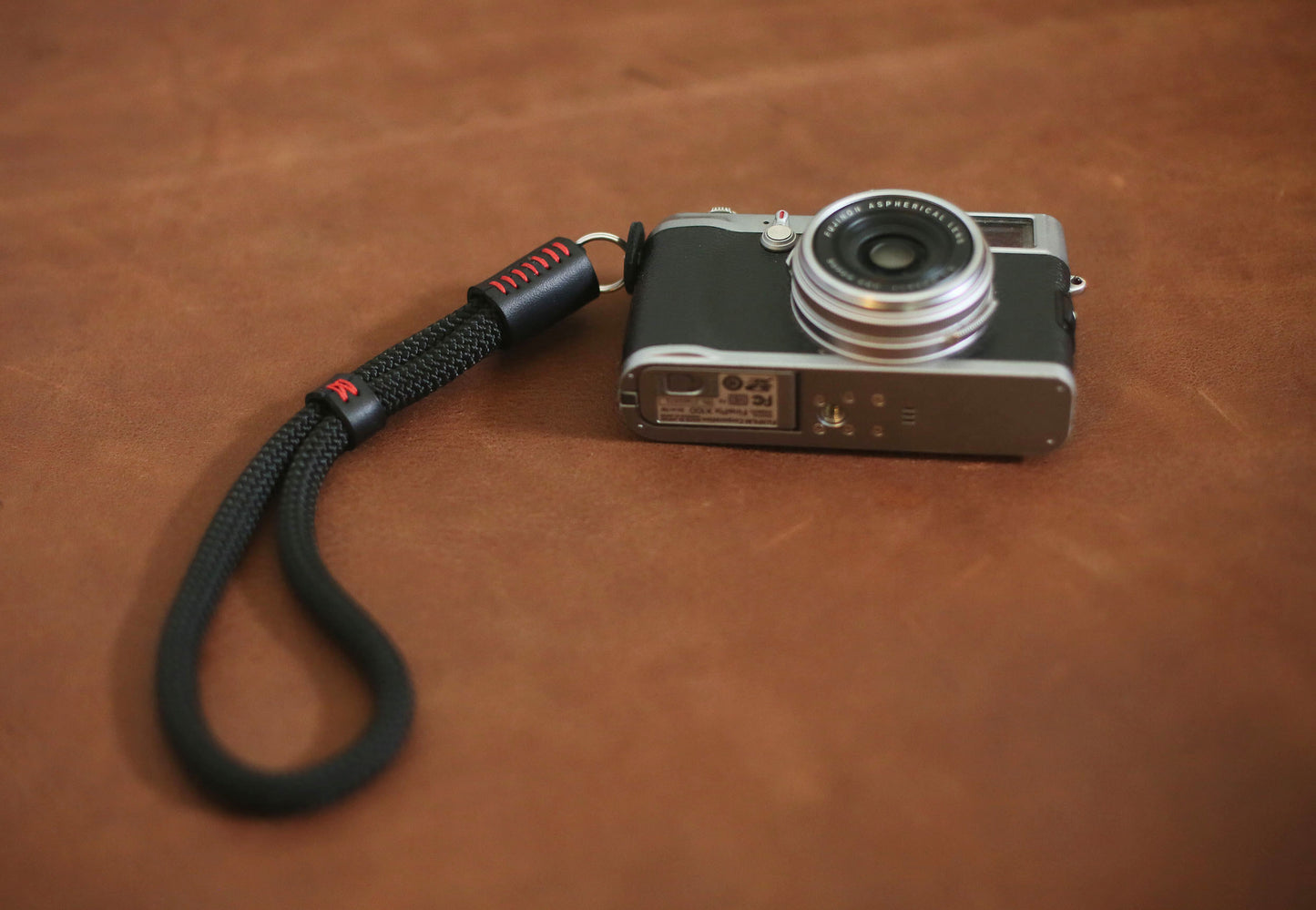 Black rope wrist strap coiled beside vintage camera