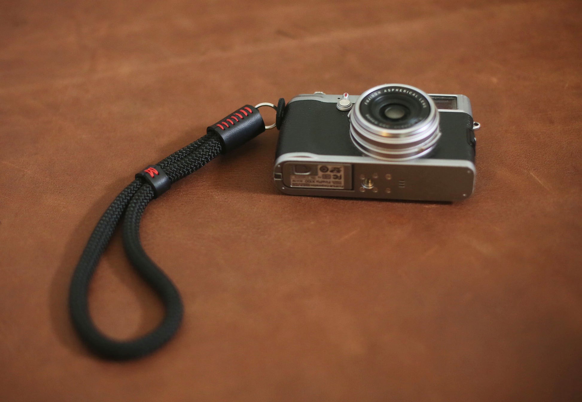 Black rope wrist strap coiled beside vintage camera