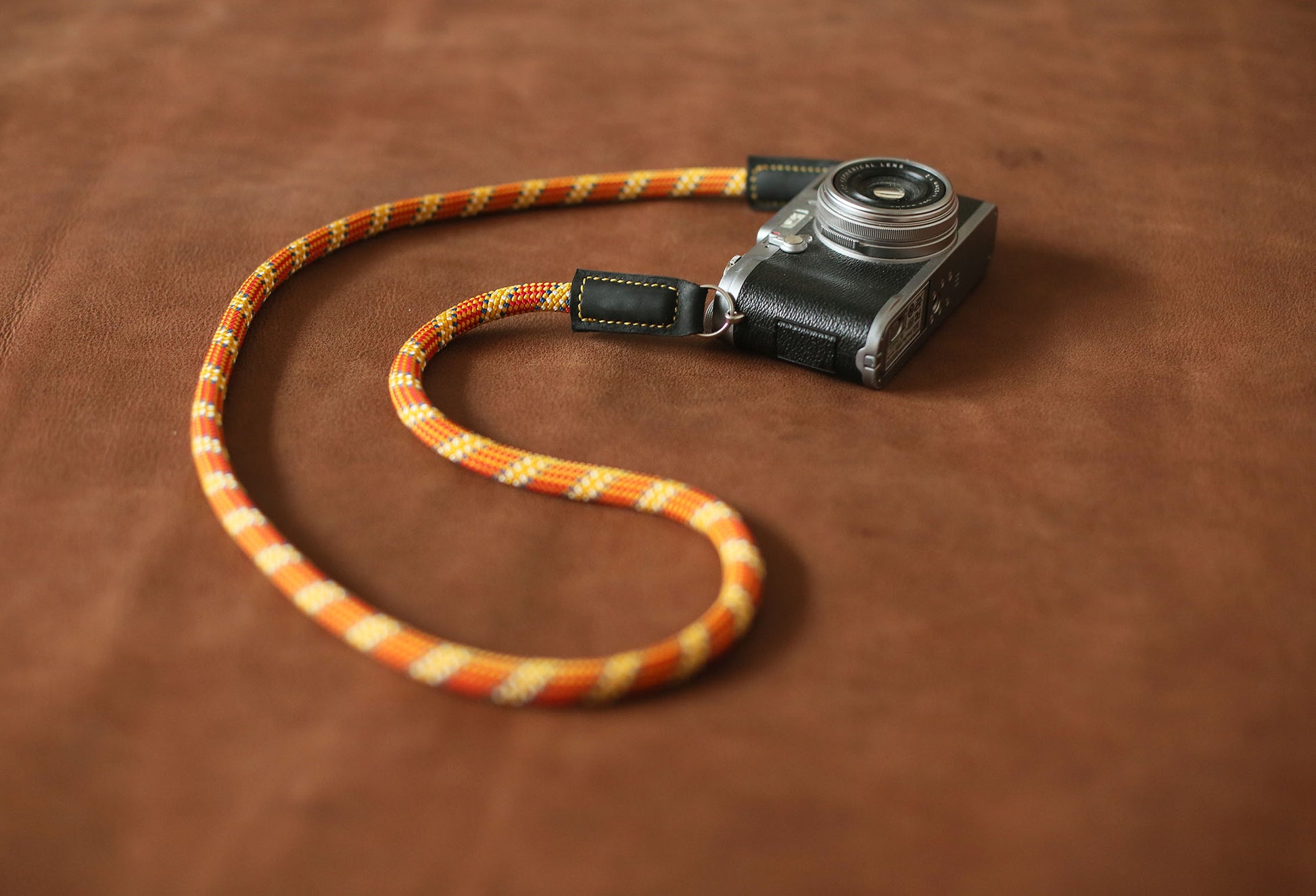 Orange climbing rope camera strap with golden pattern and black leather ends
