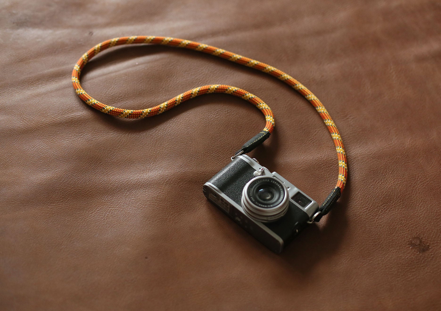 Adventure-ready orange rope camera strap with golden weave