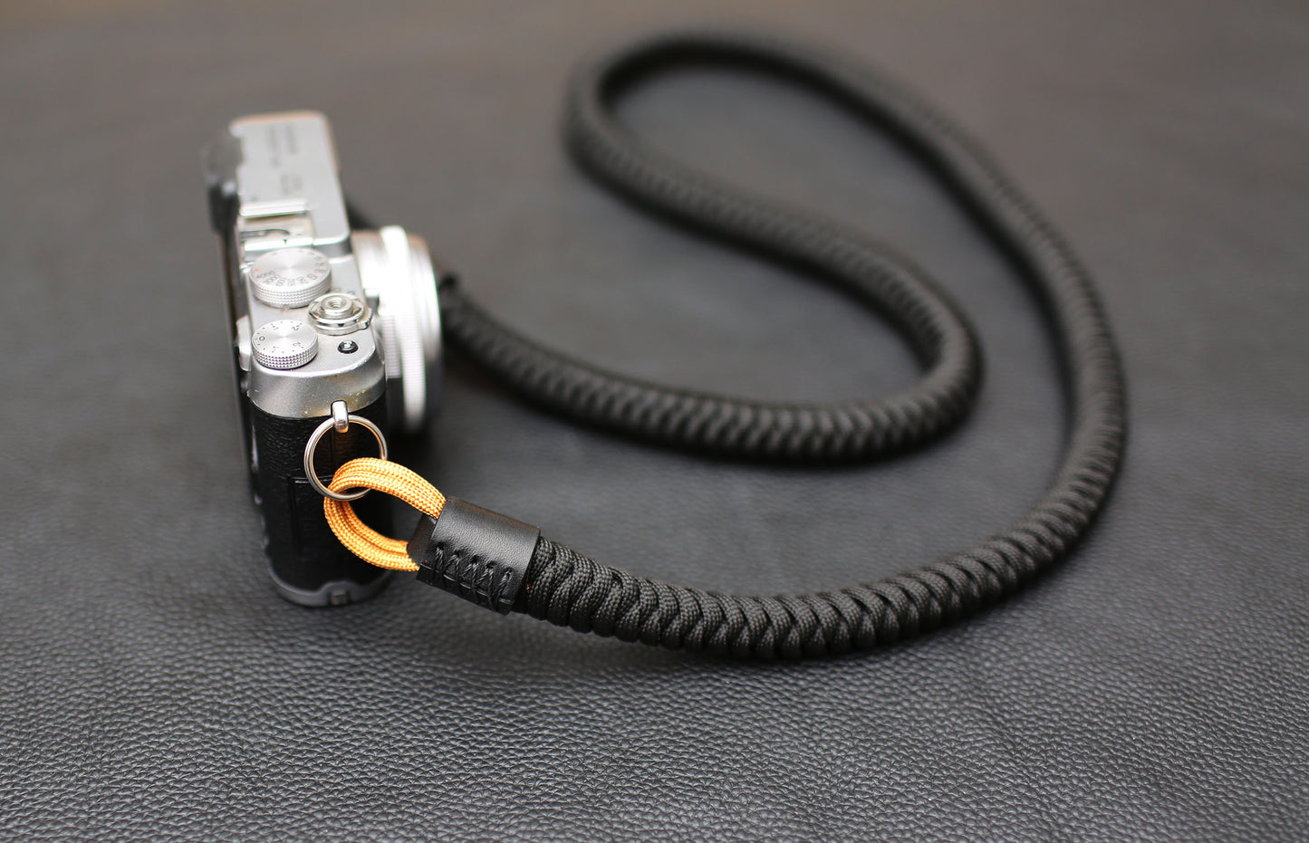 	Handwoven black and gold paracord camera strap attached to mirrorless camera