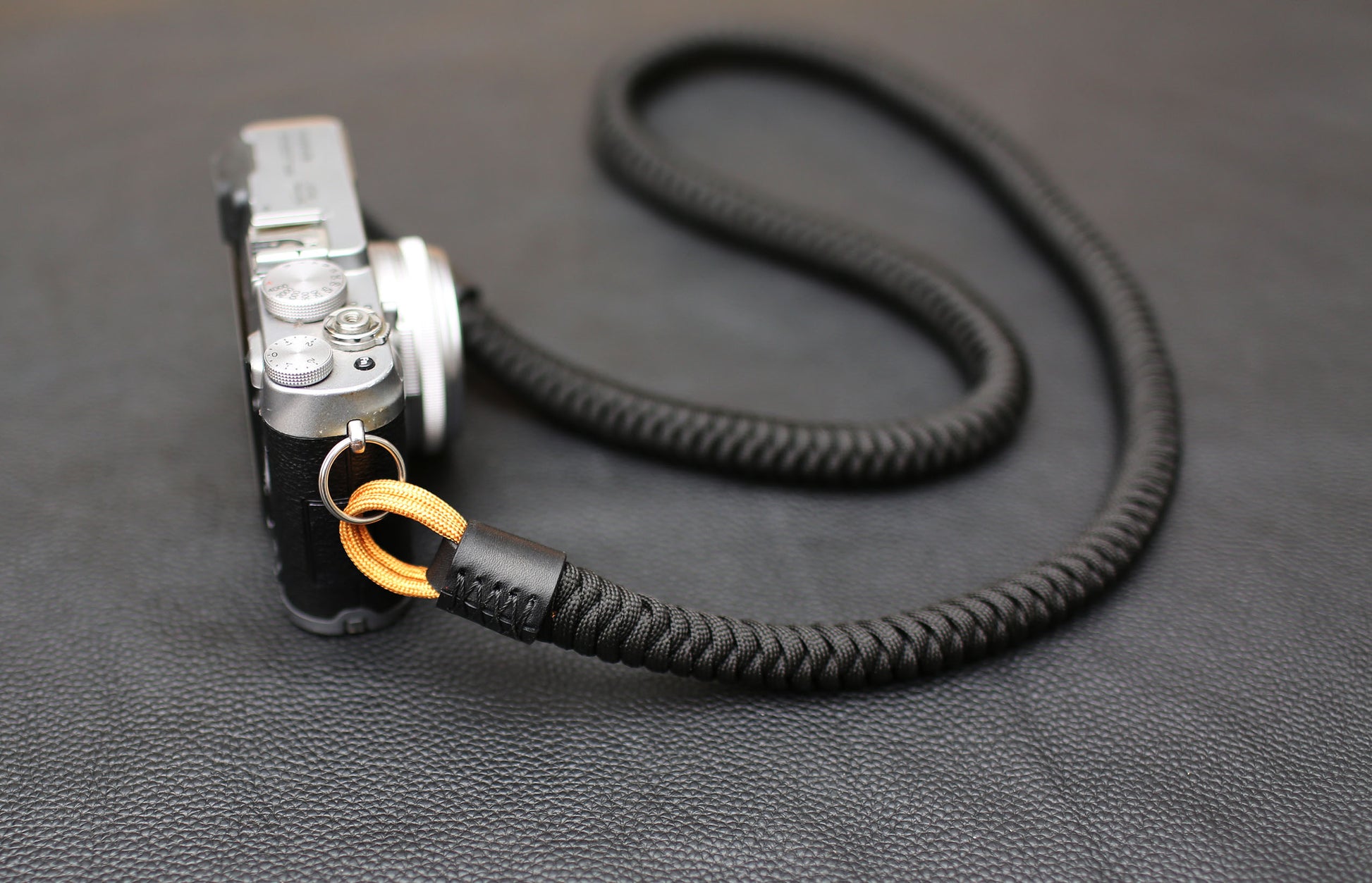 	Handwoven black and gold paracord camera strap attached to mirrorless camera