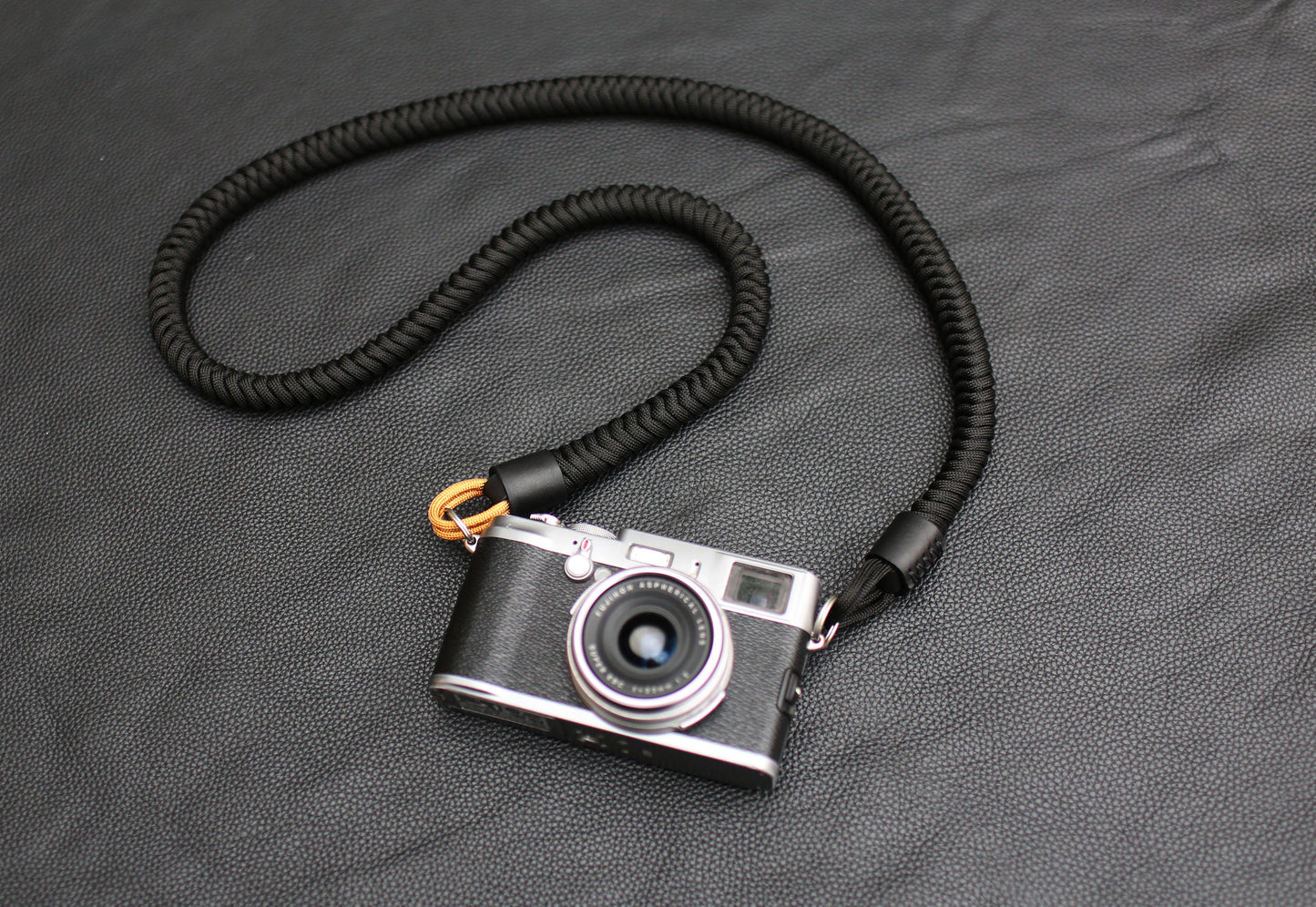Black and gold camera strap laid flat on leather background