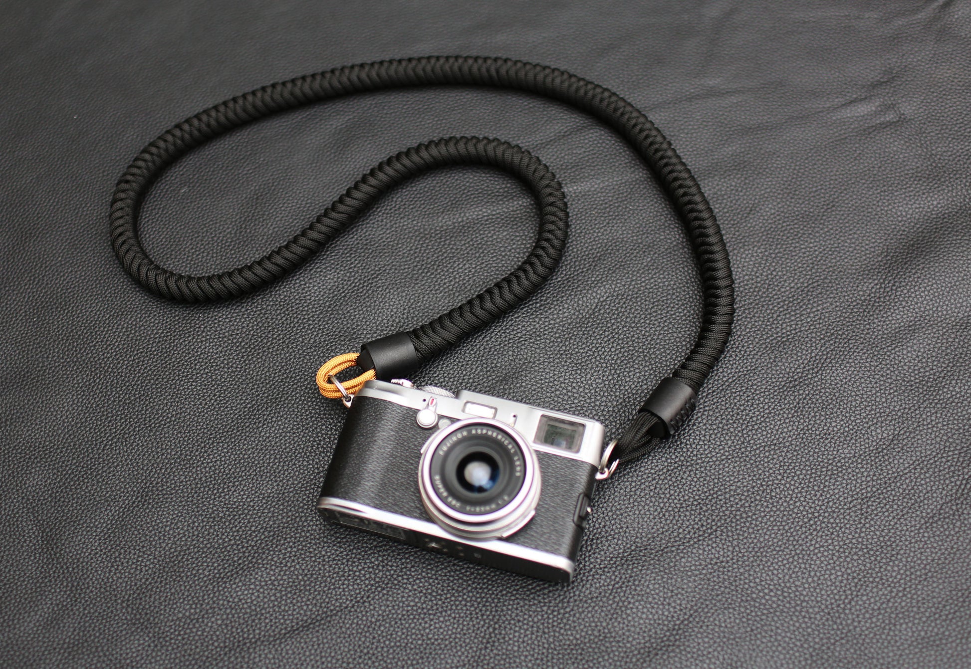Black and gold camera strap laid flat on leather background