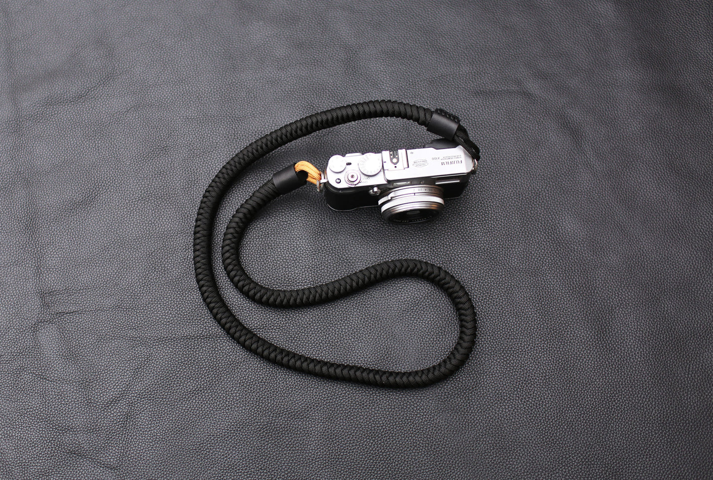 Handcrafted black and gold camera strap coiled on table