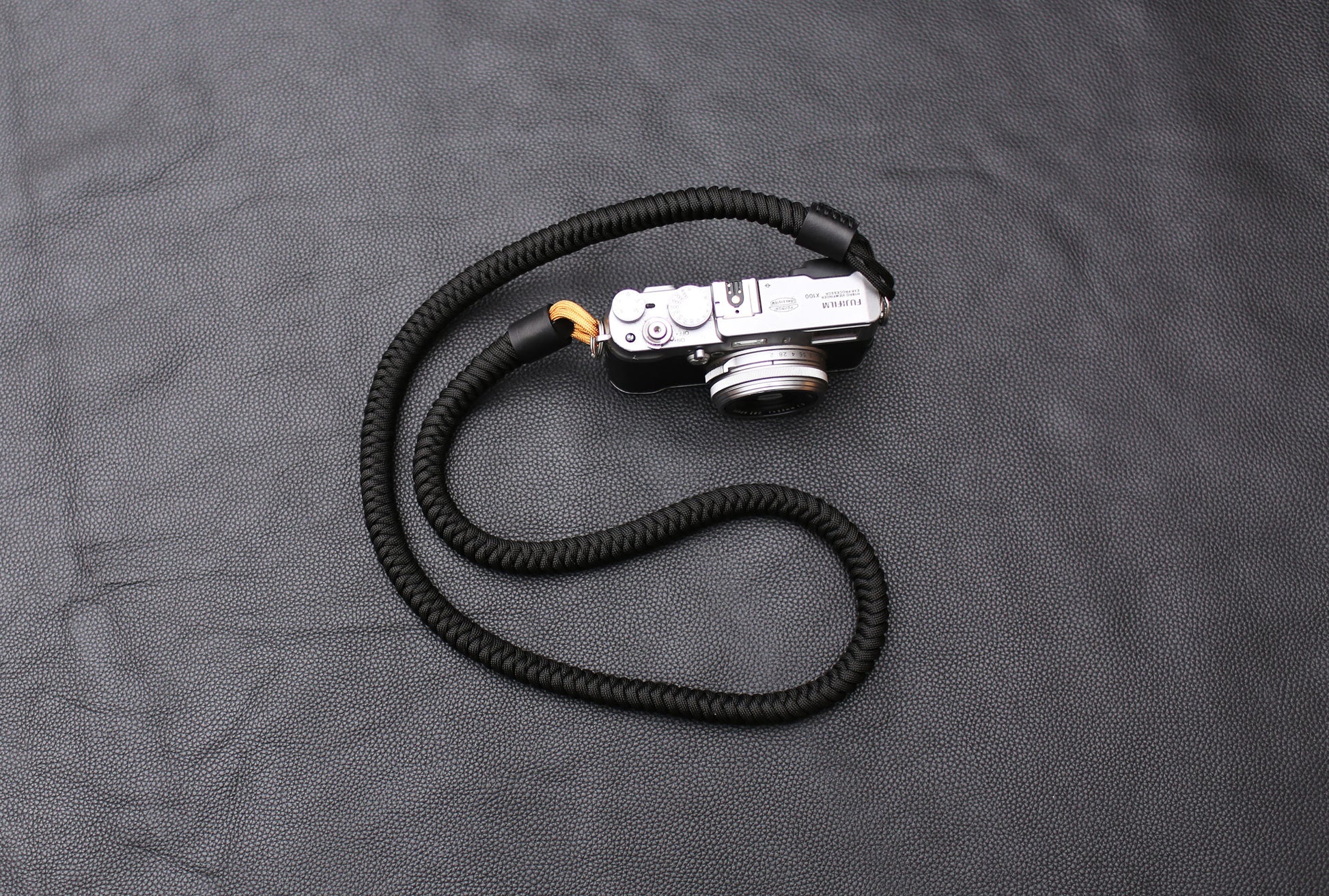 Handcrafted black and gold camera strap coiled on table