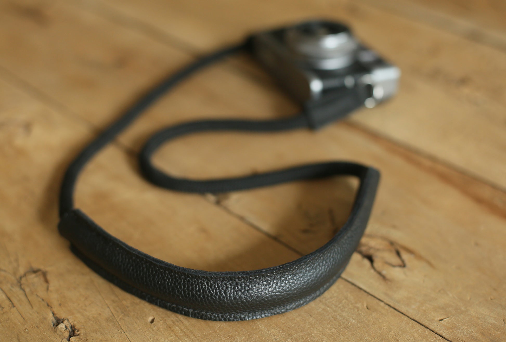 Black rope camera strap worn crossbody with shoulder pad on photographer