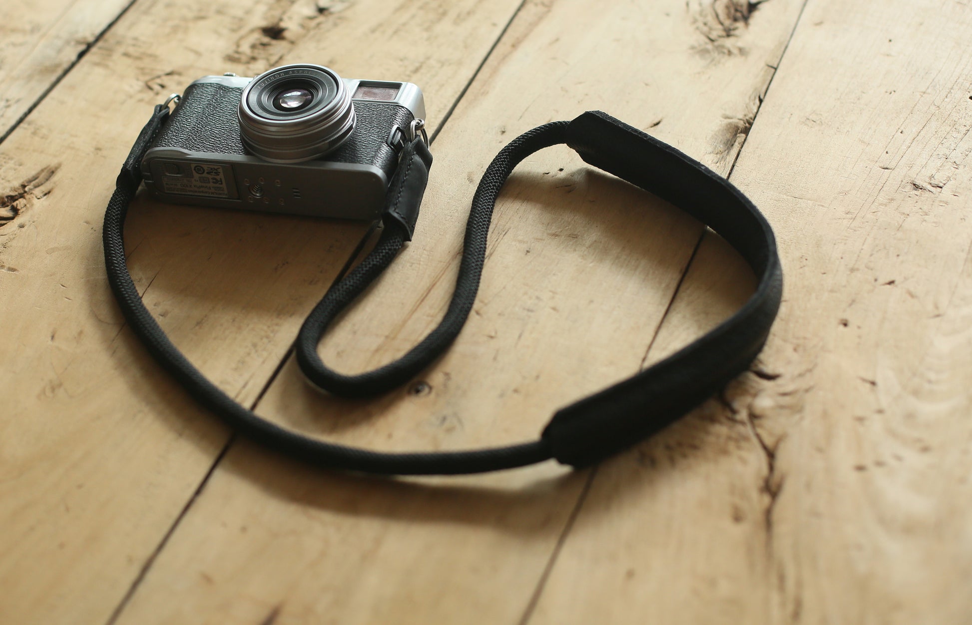 Black rope camera strap attached to film camera showing full setup