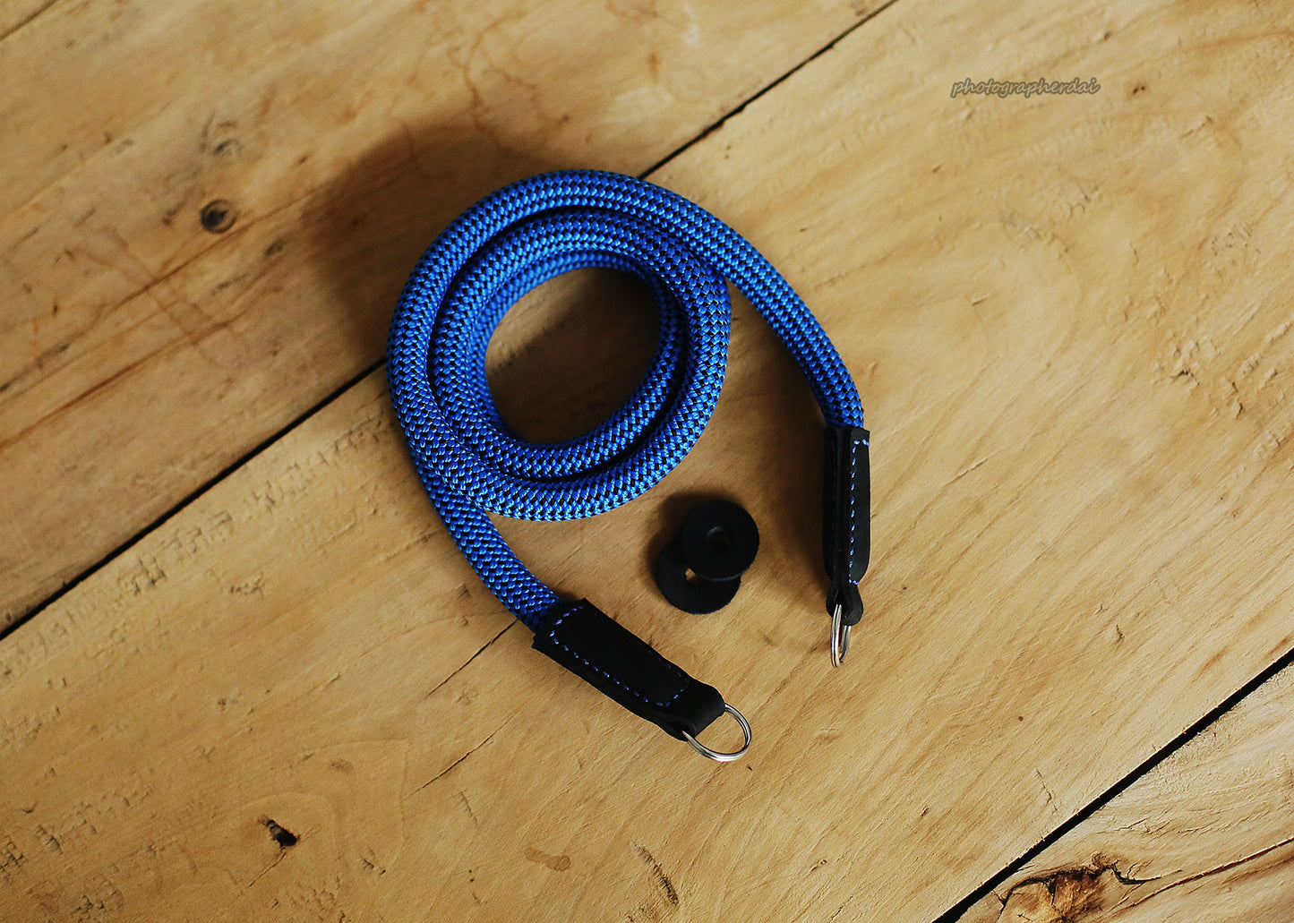 Leather joint and metal connection detail on blue camera strap with dotted pattern