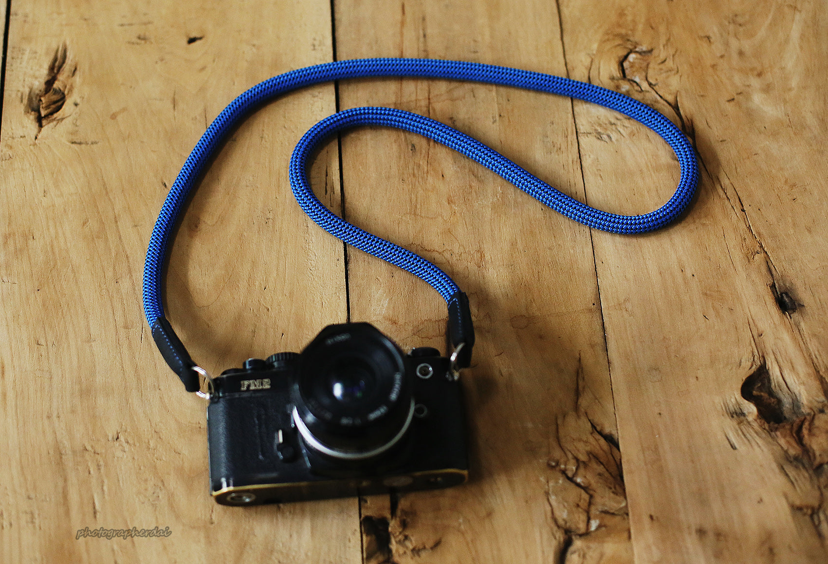 Minimal product scene of blue rope strap with dotted weave beside camera