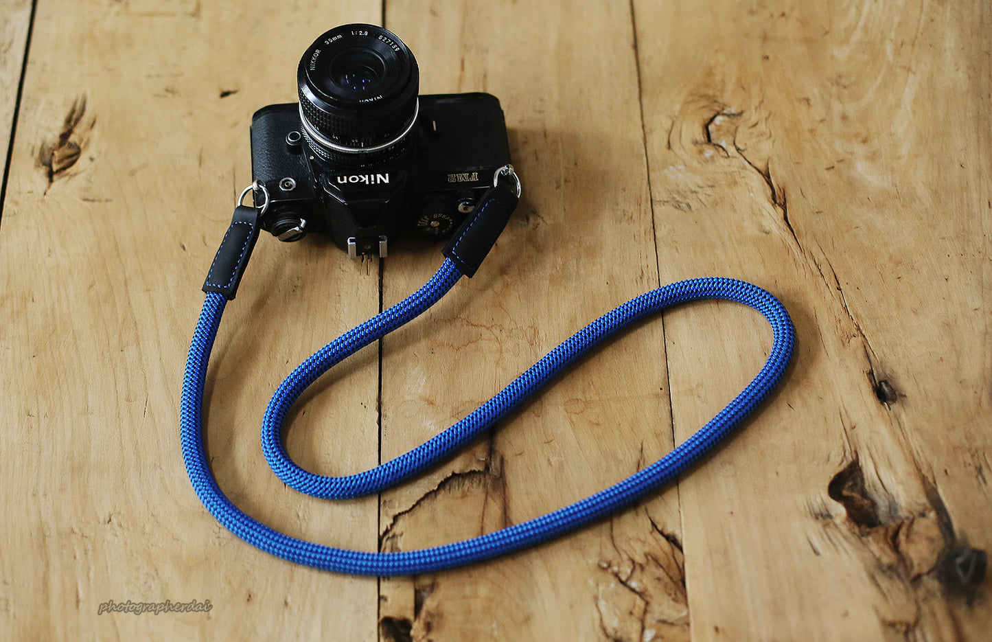 Blue dotted climbing rope camera strap forming a loop on wooden surface
