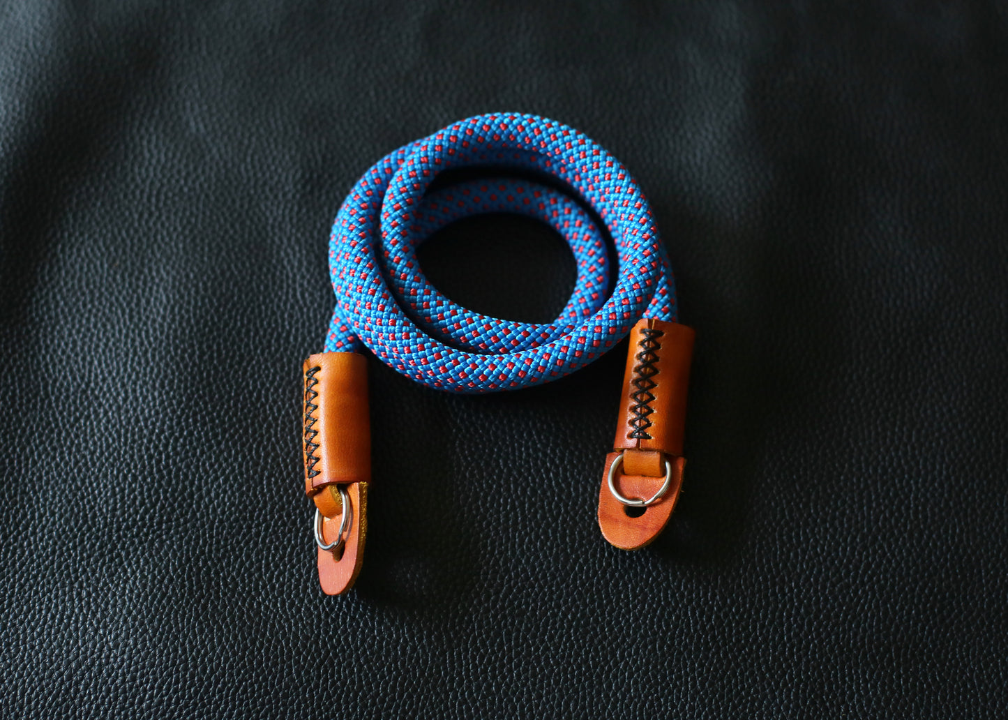blue red rope camera strap on black leather background