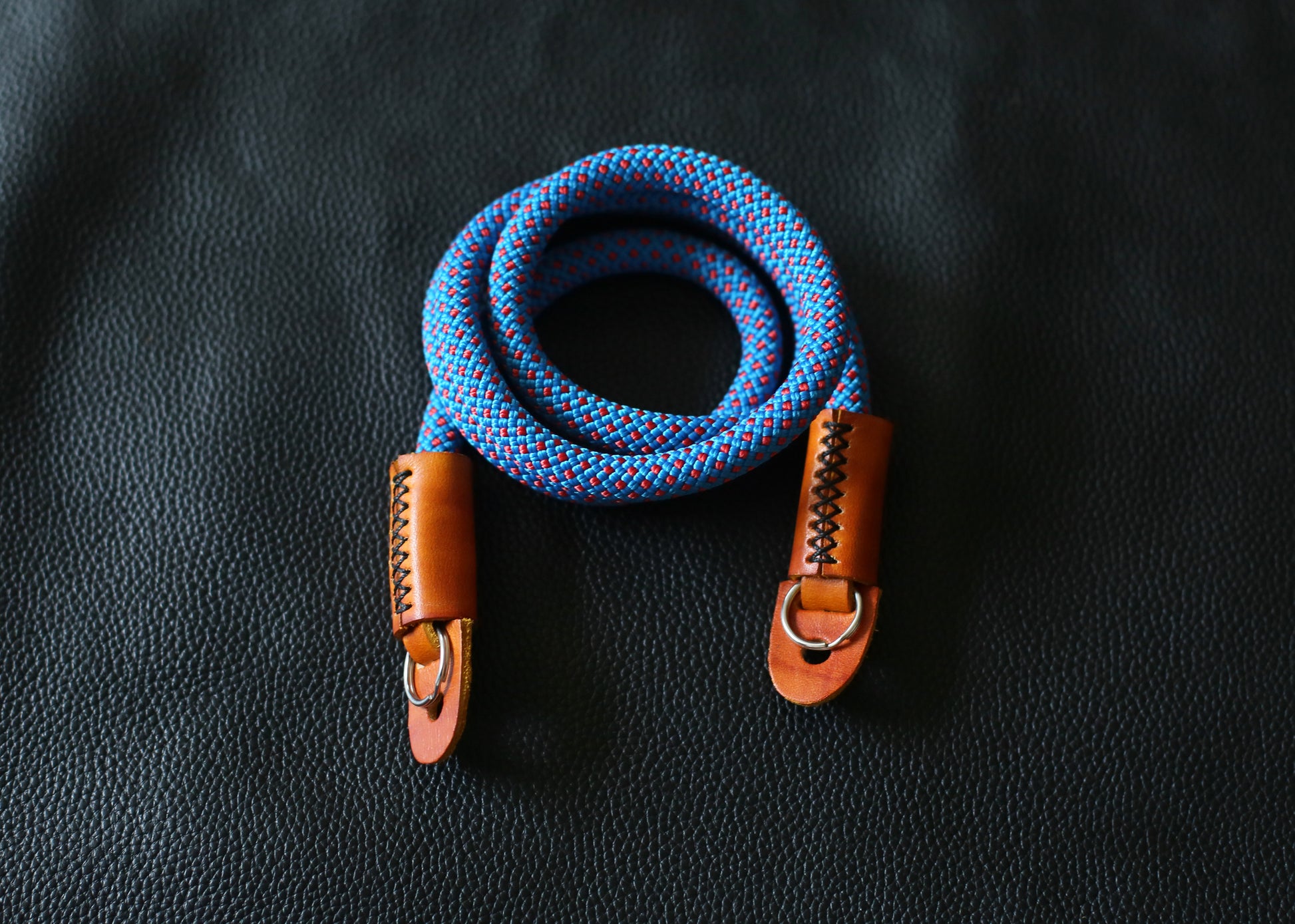 blue red rope camera strap on black leather background