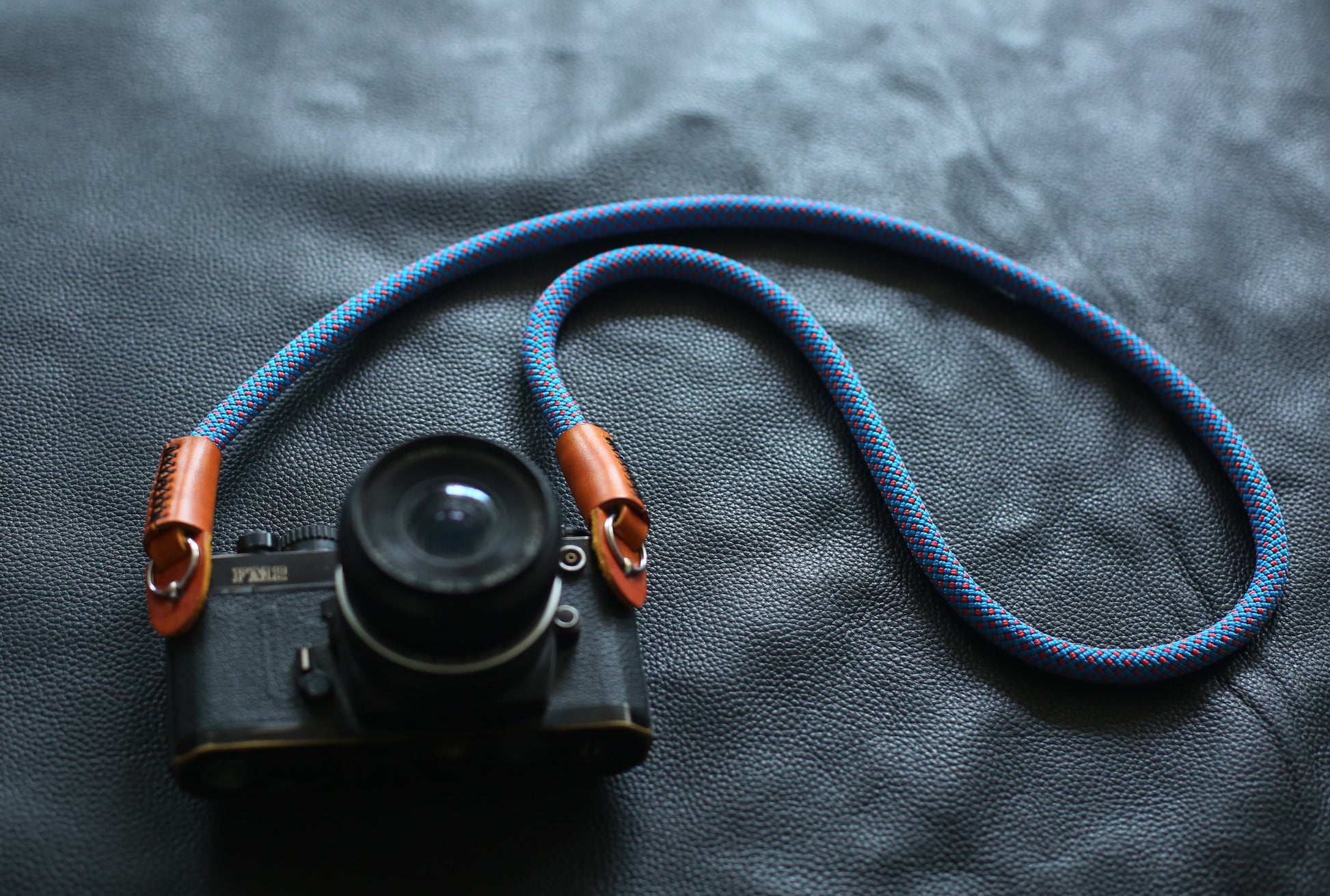 blue red rope camera strap on black leather background