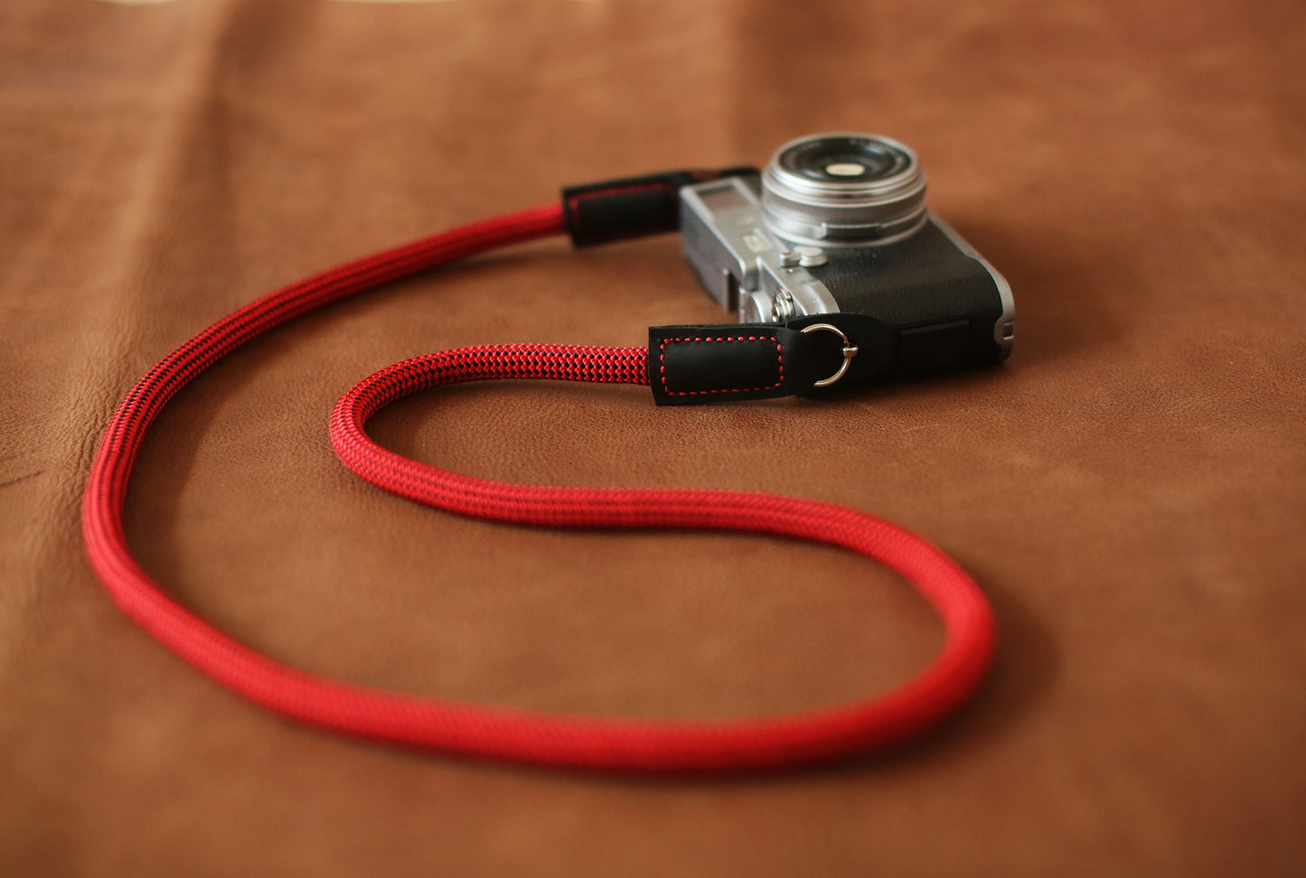 Red and black speckled camera strap hanging on camera