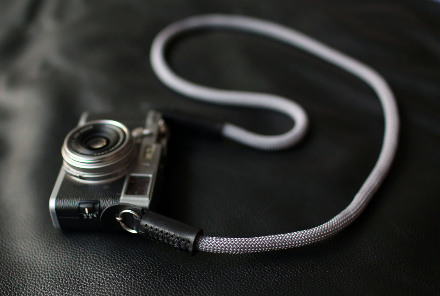 Handmade gray rope camera strap attached to silver mirrorless camera