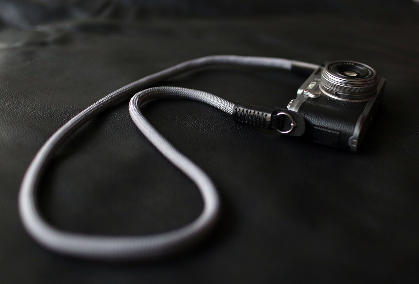 Gray climbing rope camera strap on black leather background