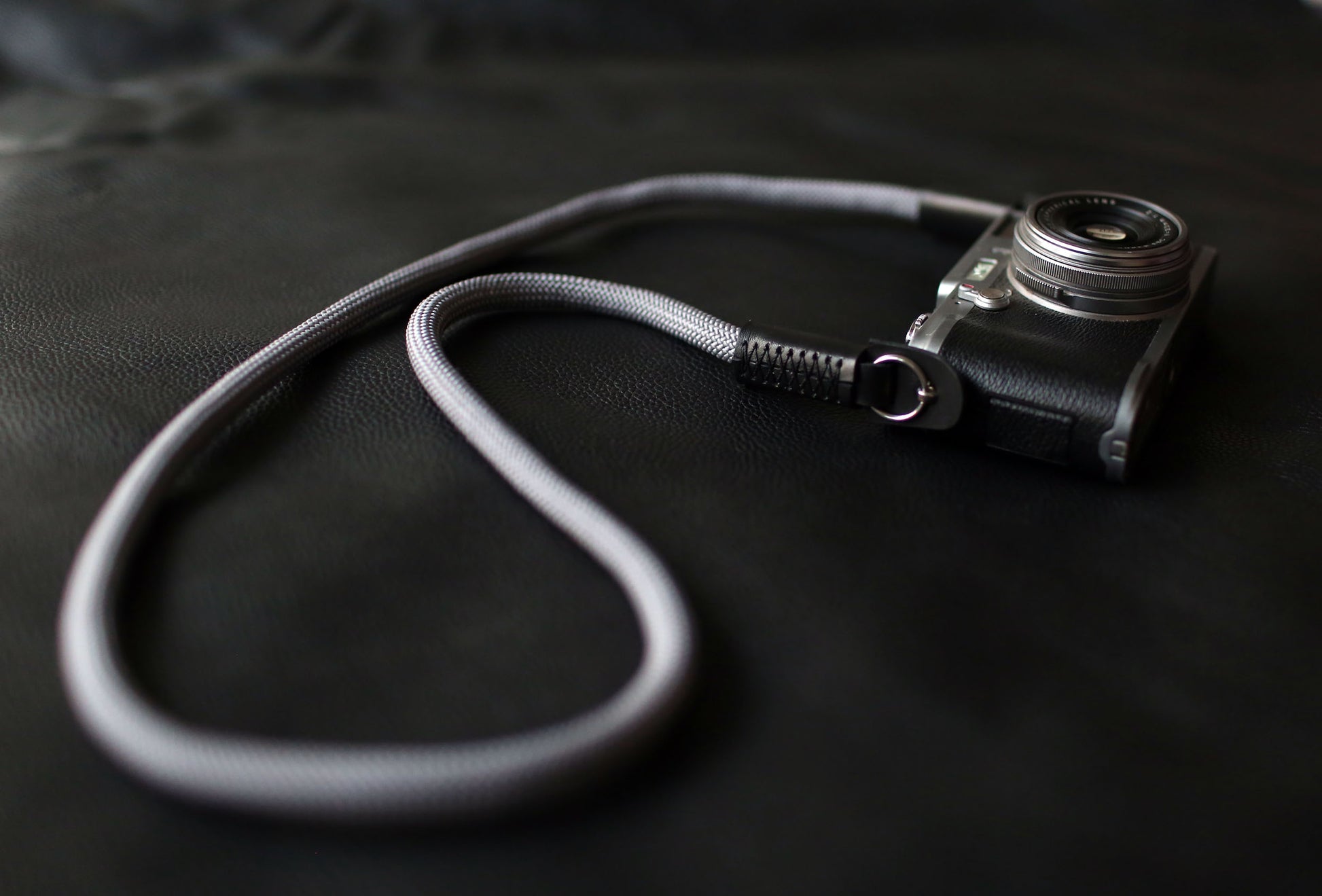 Gray climbing rope camera strap on black leather background