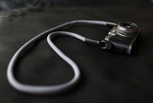 Gray climbing rope camera strap on black leather background