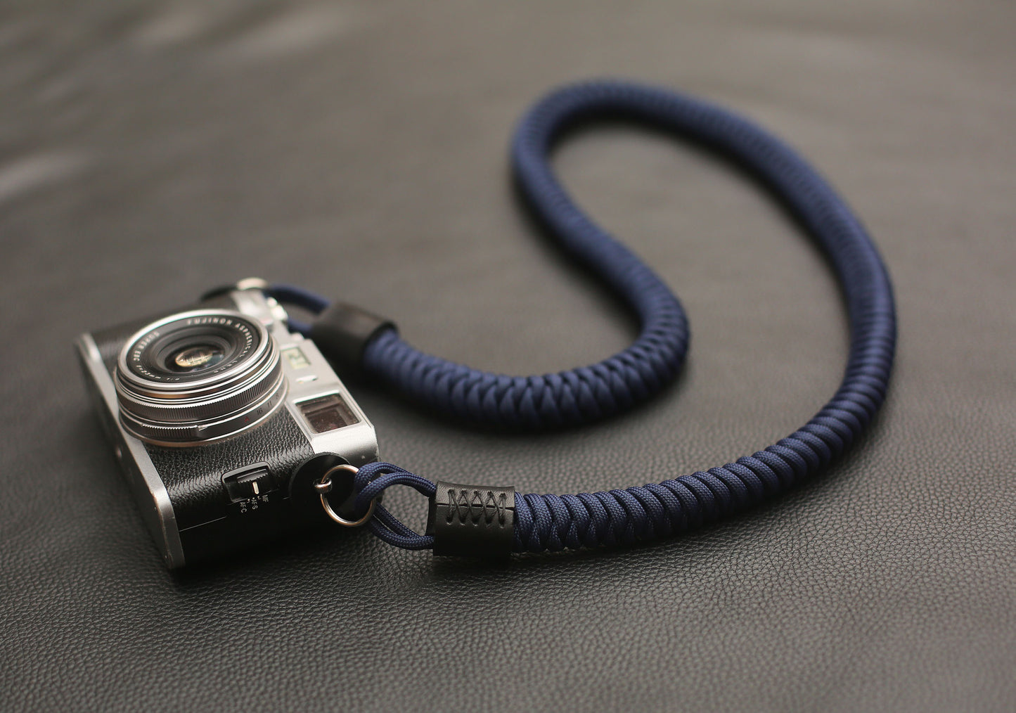 Cylindrical leather end and metal clasp detail on navy strap