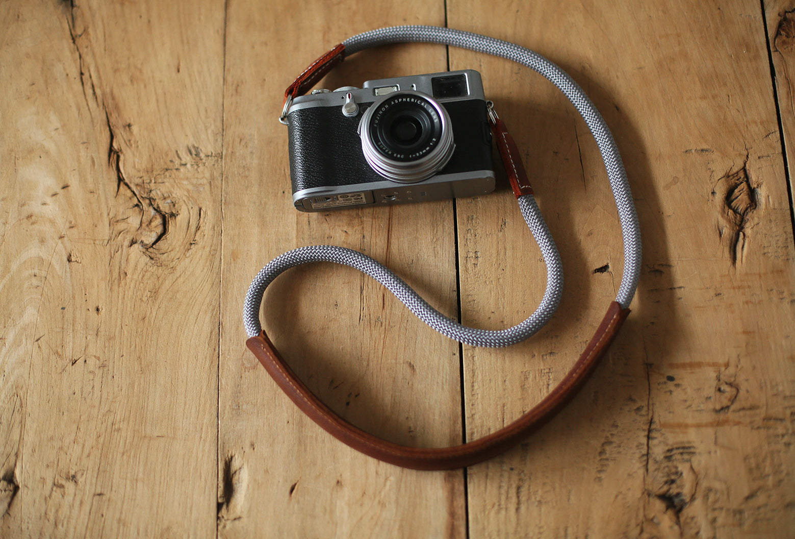 Gray rope camera strap connected to silver Fujifilm camera