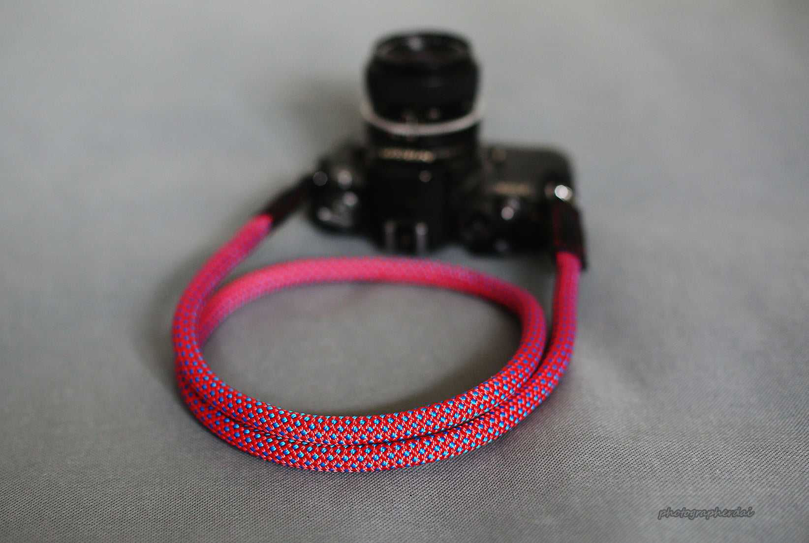Purple climbing rope camera strap worn crossbody on photographer