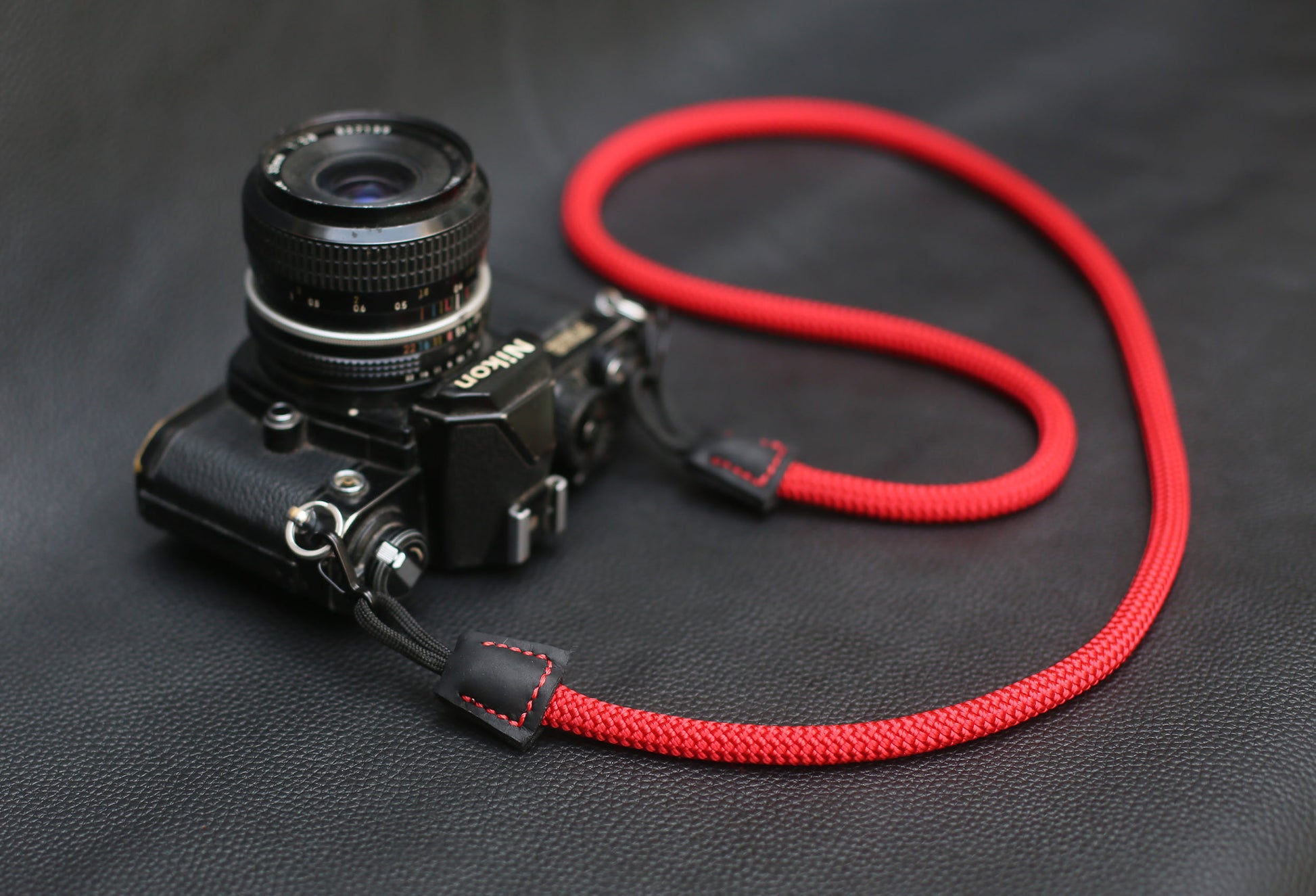 Red climbing rope strap coiled on black leather surface