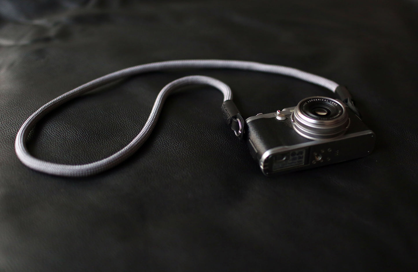 Gray rope camera strap with metal ring and leather guard