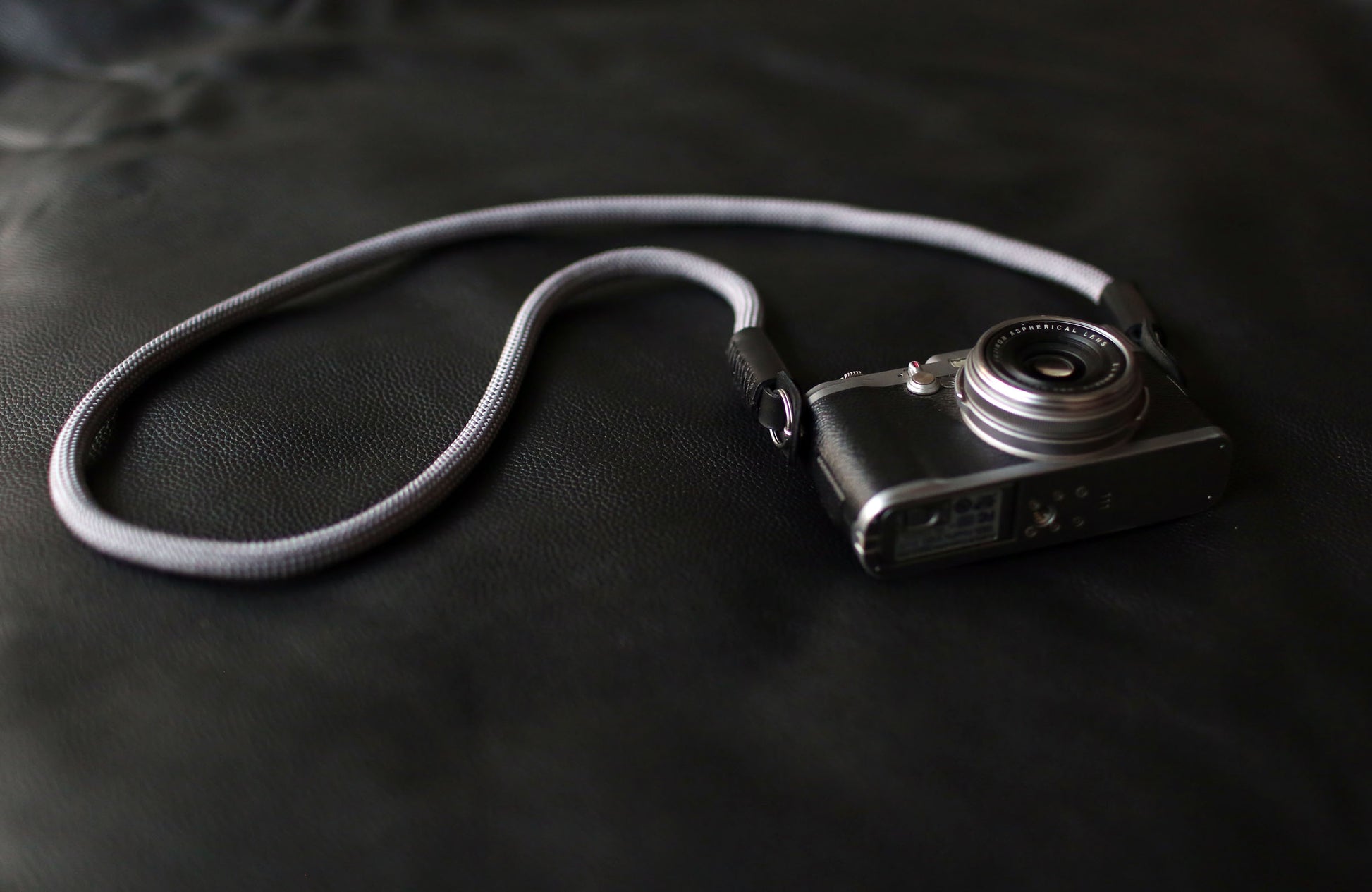 Gray rope camera strap with metal ring and leather guard