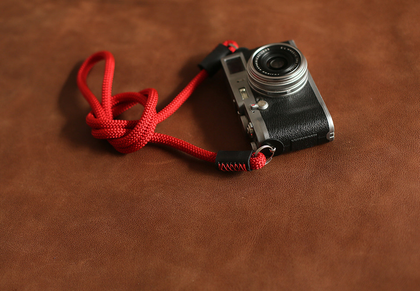 Leather and metal ring connection detail on red rope strap
