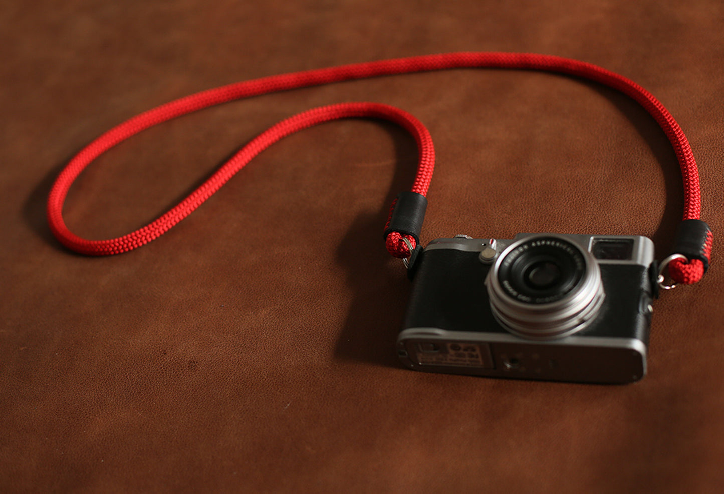 Loop formation of red rope camera strap beside film camera