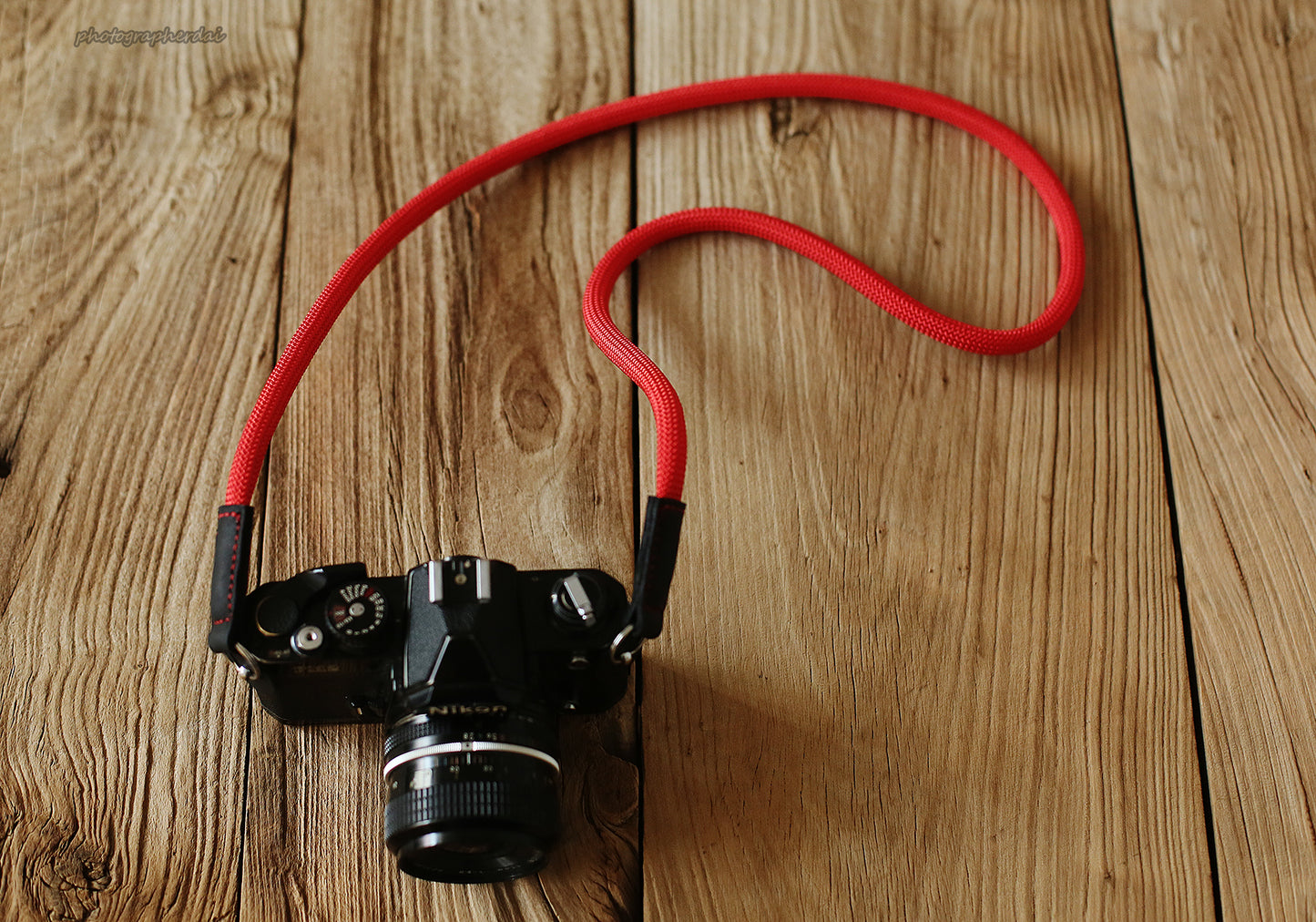 Red climbing rope camera strap attached to classic film camera body
