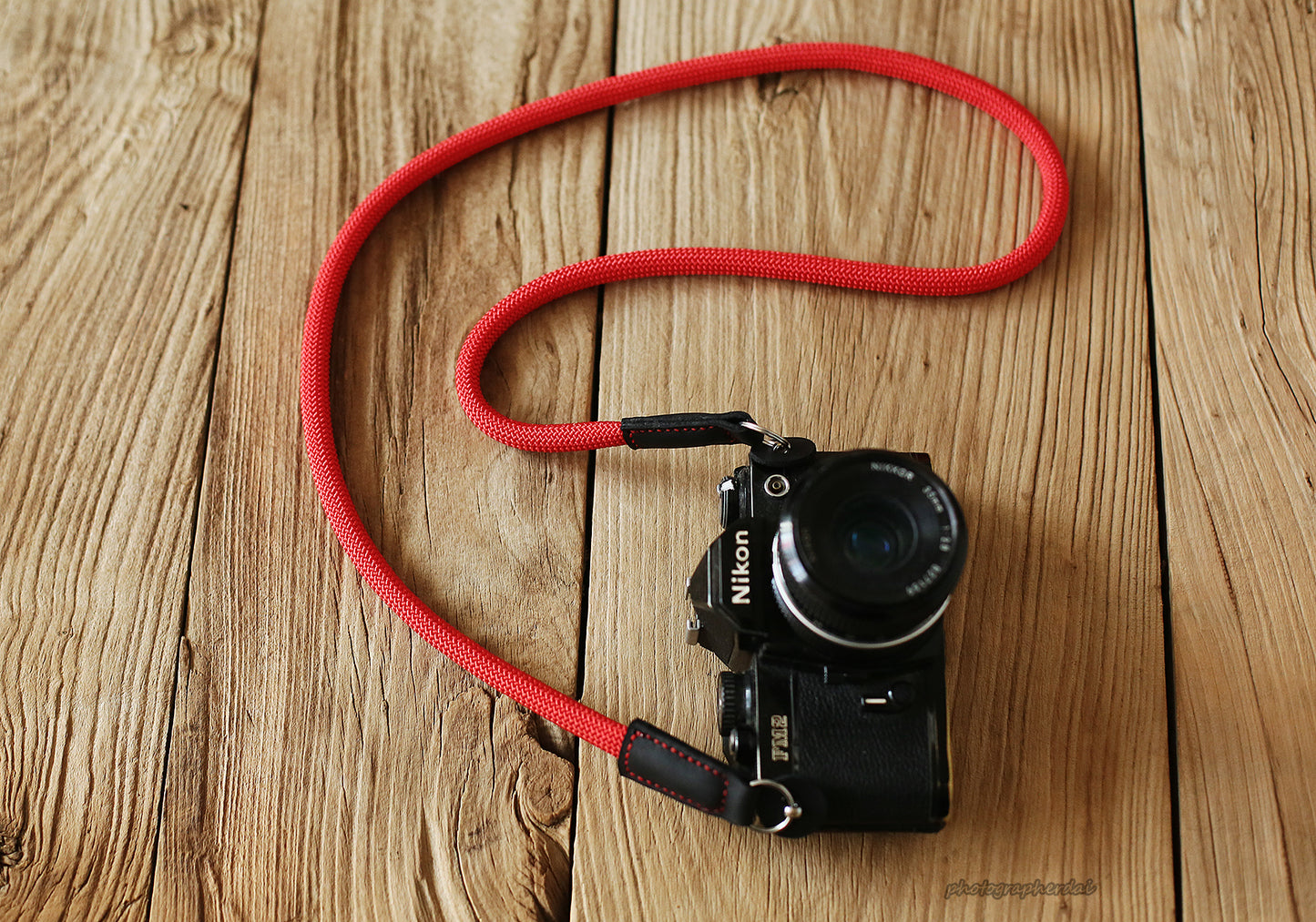 Close up of solid red rope texture and leather joint on camera strap