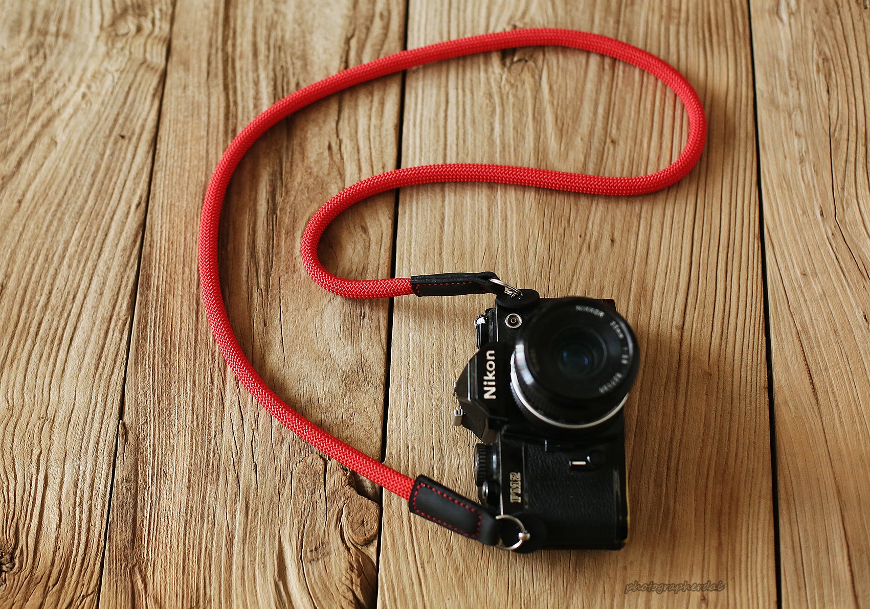 Close up of solid red rope texture and leather joint on camera strap