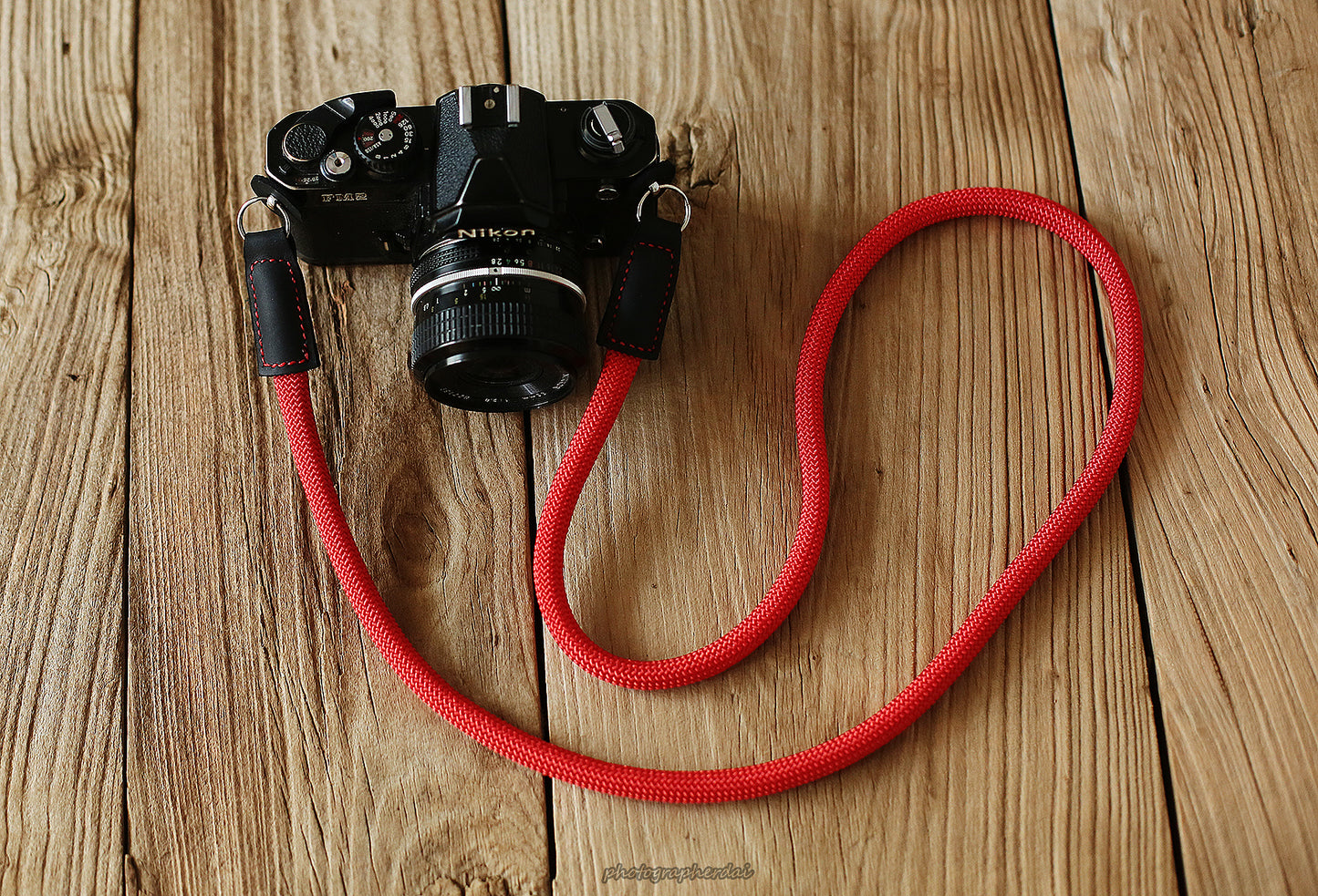 Red rope camera strap forming a loose loop next to camera
