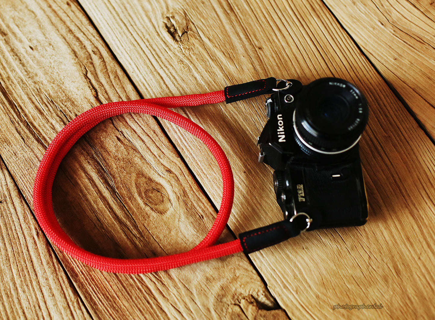 Side angle view of red climbing rope strap connected to camera lugs