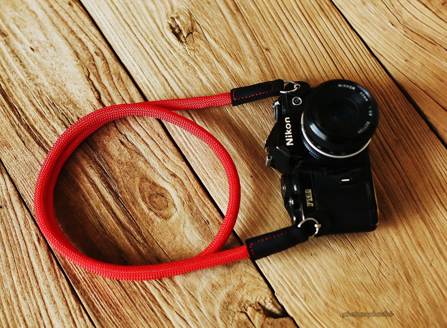 Side angle view of red climbing rope strap connected to camera lugs
