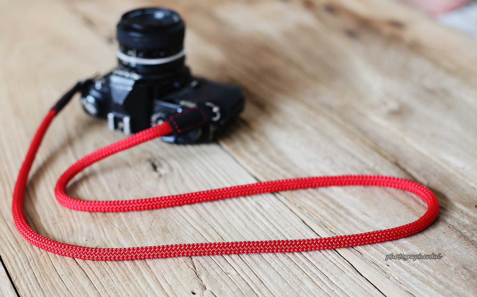 Close-up of hand-stitched black leather end on red rope strap
