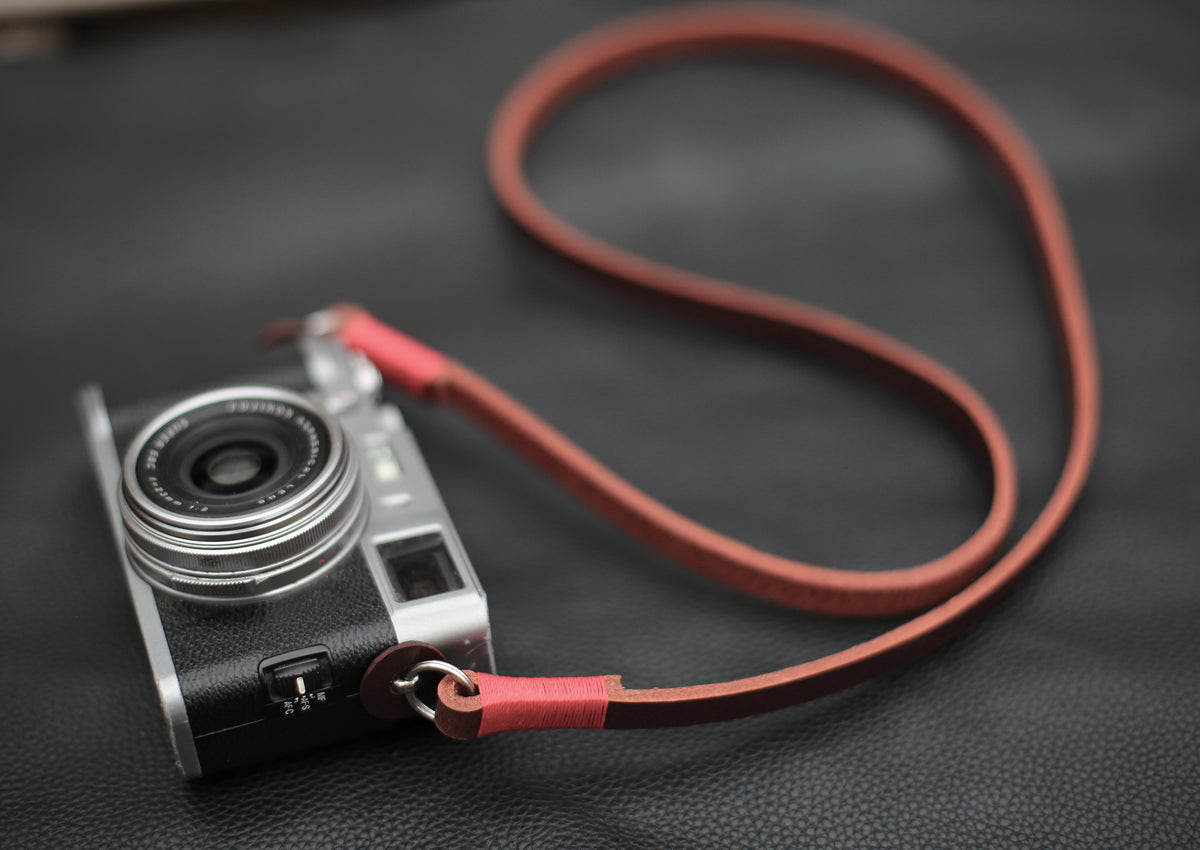 Vegetable tanned tan leather camera strap on a wooden surface