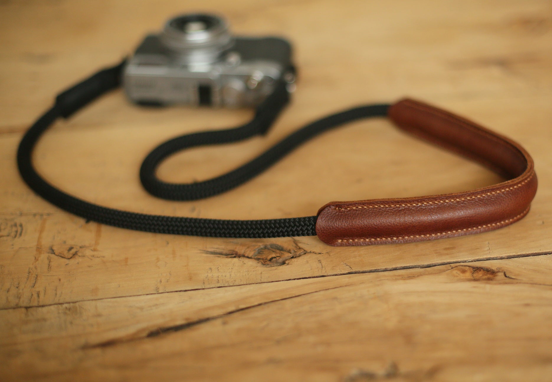 handcrafted camera strap with black rope and brown leather cushioning